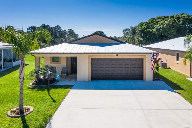 a house with a group of trees in the background under a blue sky 